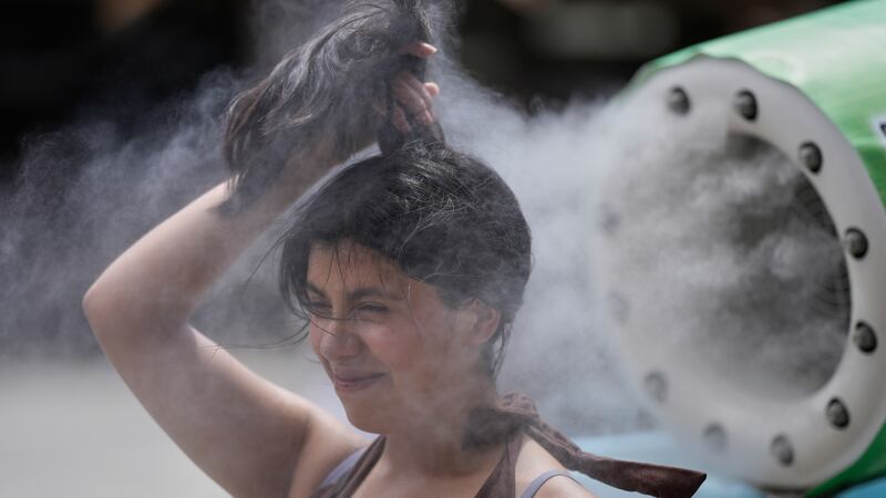 Una persona se refresca en una unidad de enfriamiento durante un caluroso día en el templo...