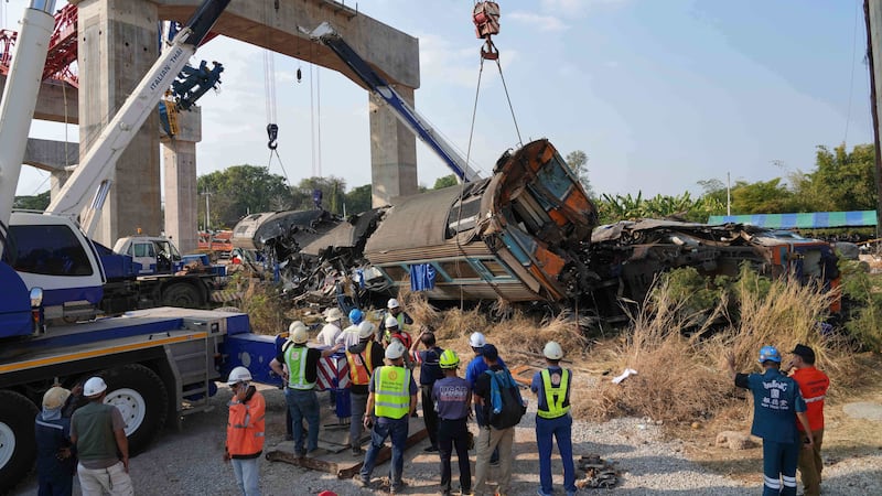 Rescatistas intentan levantar los restos después de que una grúa cayera sobre un tren de...