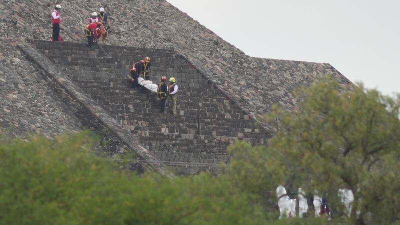 Los forenses bajan el cadáver de una víctima por una pirámide después de que, según las...