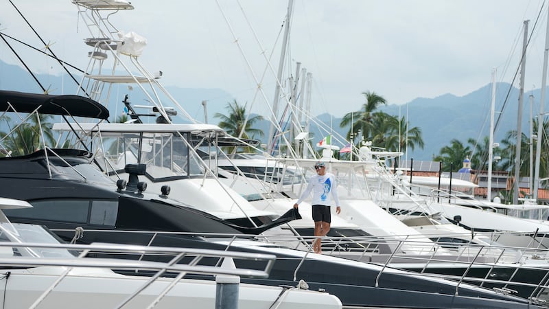 Un hombre cubre una ventana en un barco mientras el huracán Simón se acerca a Puerto Vallarta,...