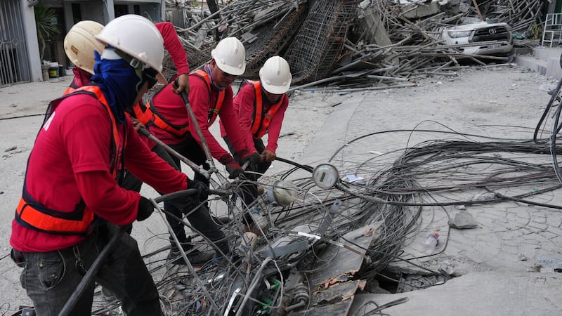 Trabajadores cortan cables durante una operación de búsqueda en un edificio derruido donde se...